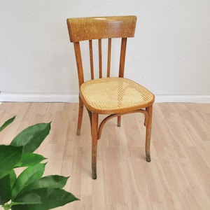 May include: A wooden chair with a woven cane seat and back. The chair has a light brown finish and is in good condition.
