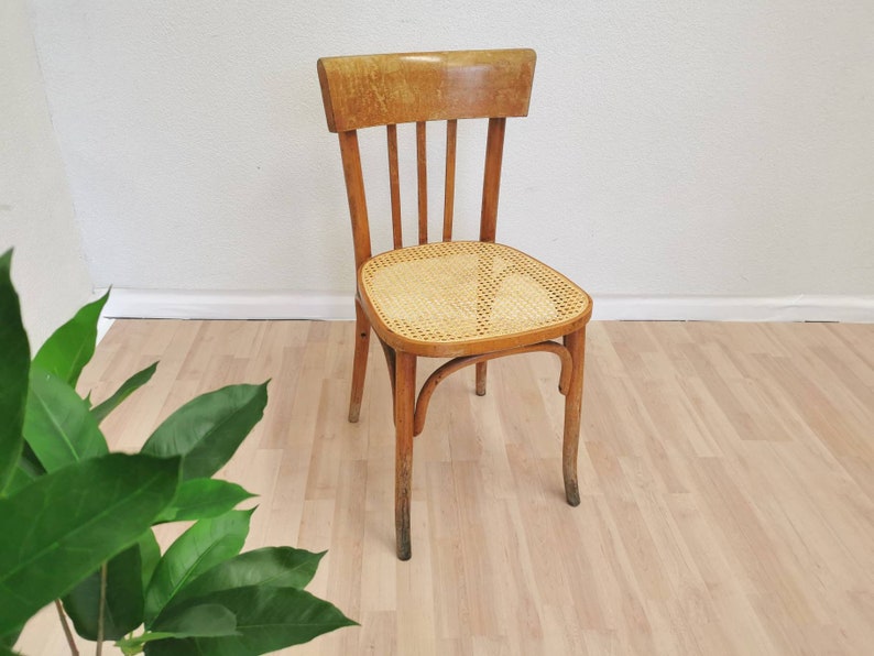 May include: A wooden chair with a woven cane seat and back. The chair has a light brown finish and is in good condition.