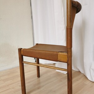 May include: A wooden chair with a brown leather seat and back. The chair has a simple design with four legs and a straight back.