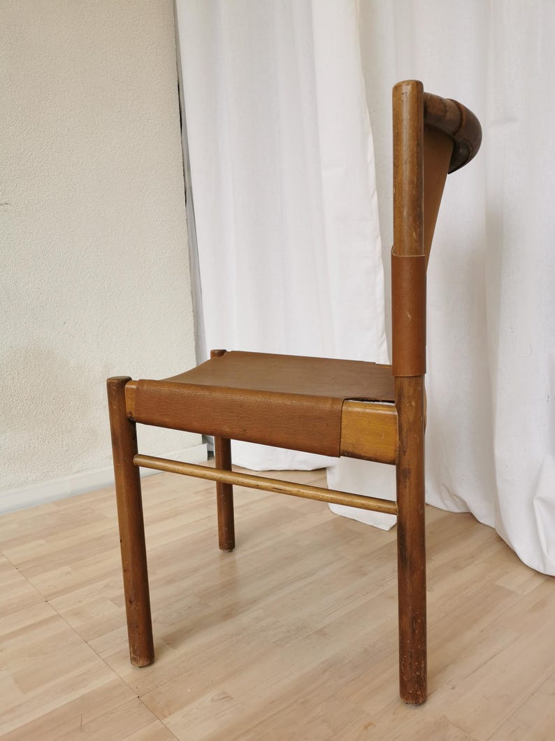 May include: A wooden chair with a brown leather seat and back. The chair has a simple design with four legs and a straight back.