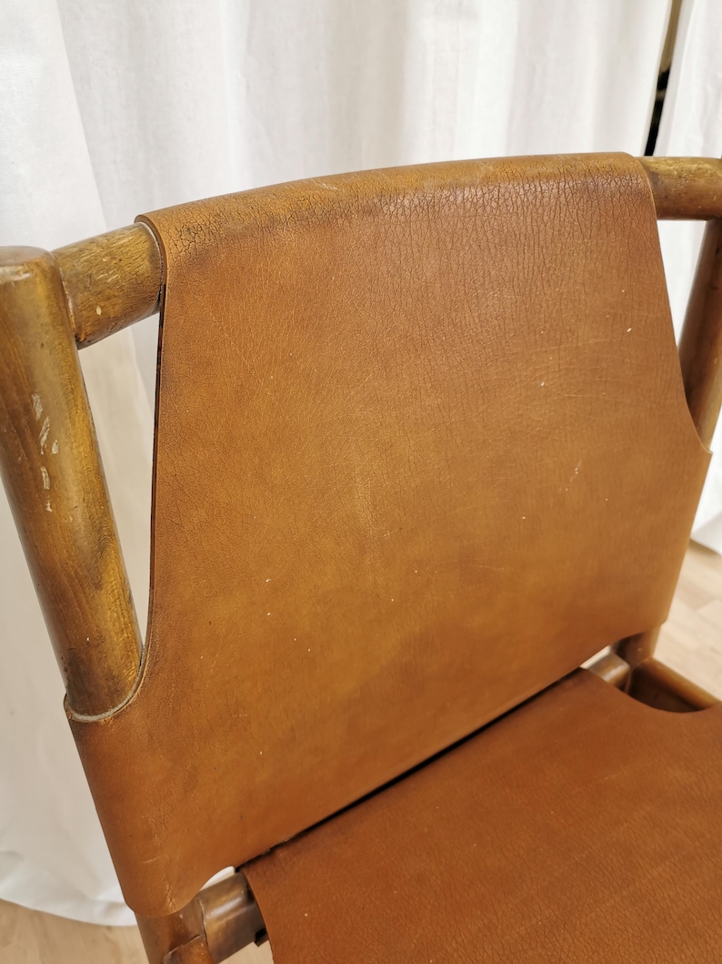 May include: A brown leather chair with a wooden frame. The chair has a high back and a wide seat.