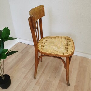 May include: A wooden chair with a woven cane seat. The chair has a simple design with a curved back and four legs.