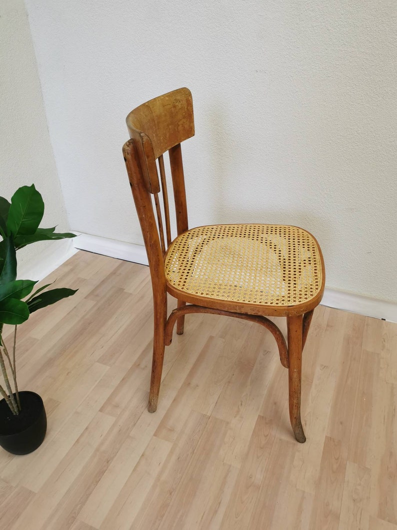 May include: A wooden chair with a woven cane seat. The chair has a simple design with a curved back and four legs.