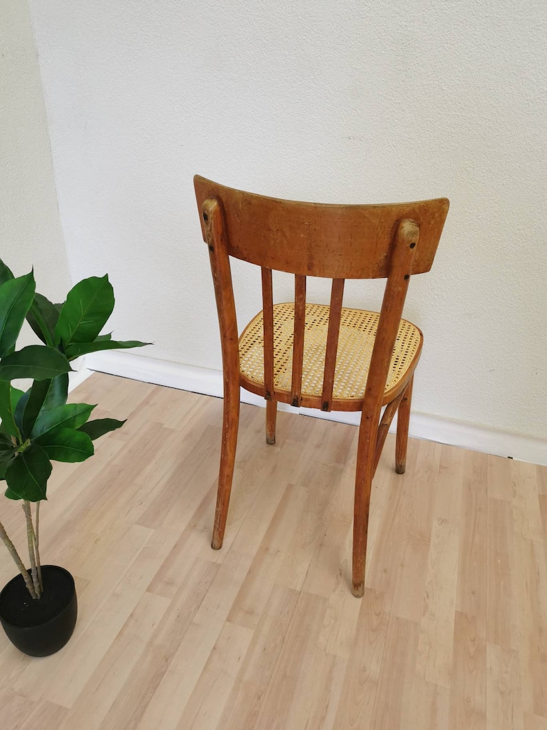May include: A wooden chair with a woven cane seat and a curved back. The chair is light brown in color and has a simple design.