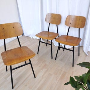 May include: Three wooden chairs with black metal frames. The chairs have a simple design with a rectangular seat and backrest.