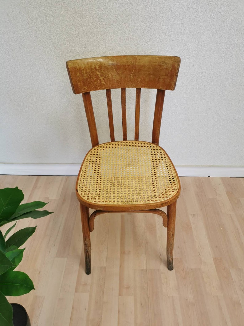 May include: A wooden chair with a woven cane seat. The chair has a simple design with a curved back and four legs.