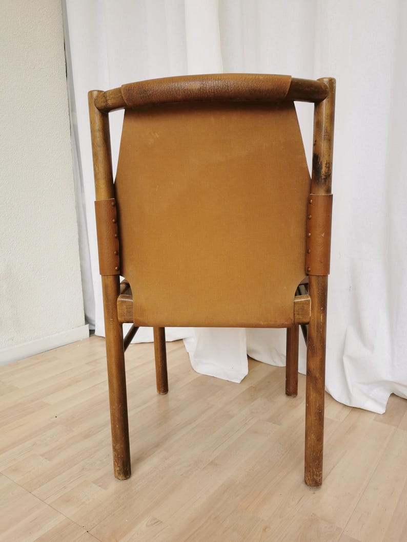 May include: A brown leather chair with a wooden frame. The chair has a simple design with a high back and four legs.