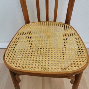May include: A wooden chair with a woven cane seat. The chair has a light brown finish and a simple design.