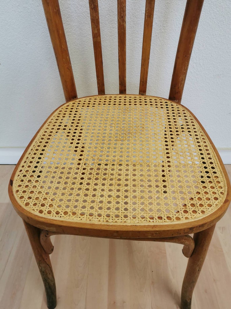 May include: A wooden chair with a woven cane seat. The chair has a light brown finish and a simple design.