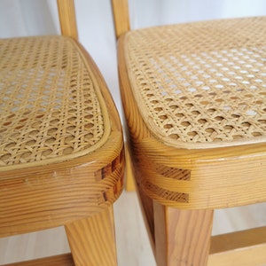 May include: Two wooden chairs with woven cane seats. The chairs are made of light wood and have a simple design.