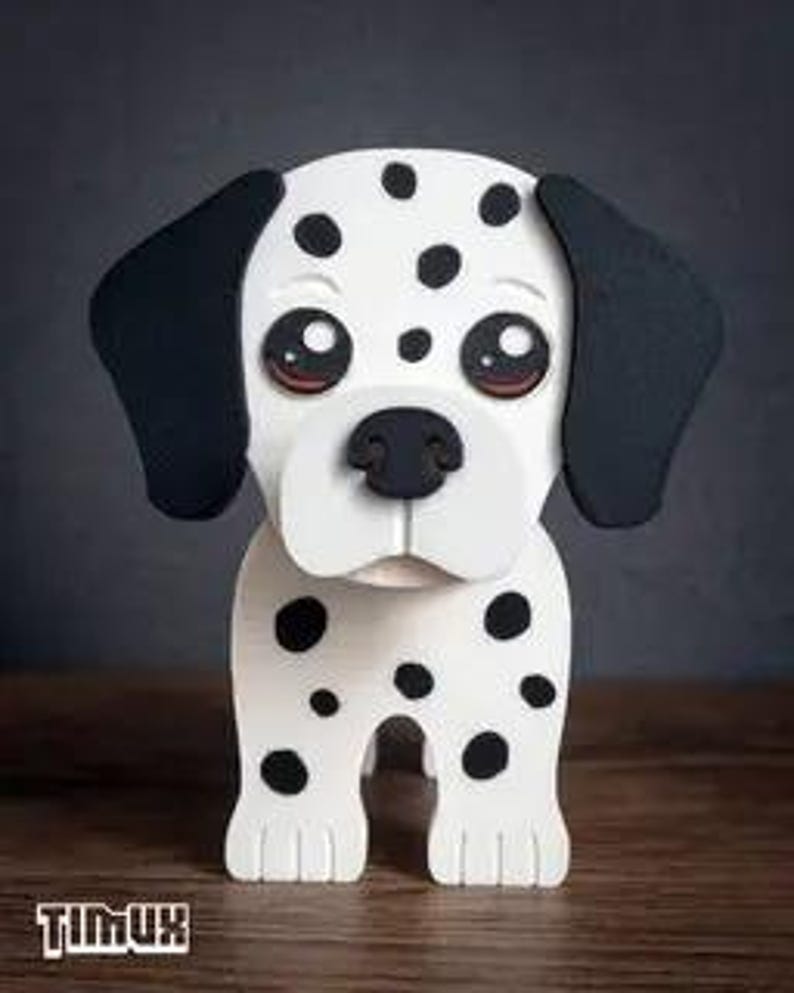 May include: A wooden Dalmatian dog figurine with a white body and black spots. The dog has large, expressive eyes, black ears, and a black nose. The figurine is standing on a wooden surface. The brand name "TIMUX" is at the bottom.