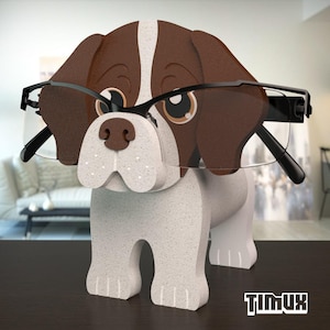 May include: A dog-shaped eyeglass holder in brown, white, and black. The holder has a cartoonish design with a white and brown body, brown ears, and a white stripe down the head. Black eyeglasses are resting on the dog's nose. The brand name "TIMUX" is visible.