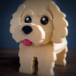 May include: A 3D printed cream-colored dog figurine with large black eyes, a black nose, and a small pink tongue. The figure features textured, layered surfaces and the word TIMUX is embossed in the lower left corner of the image.