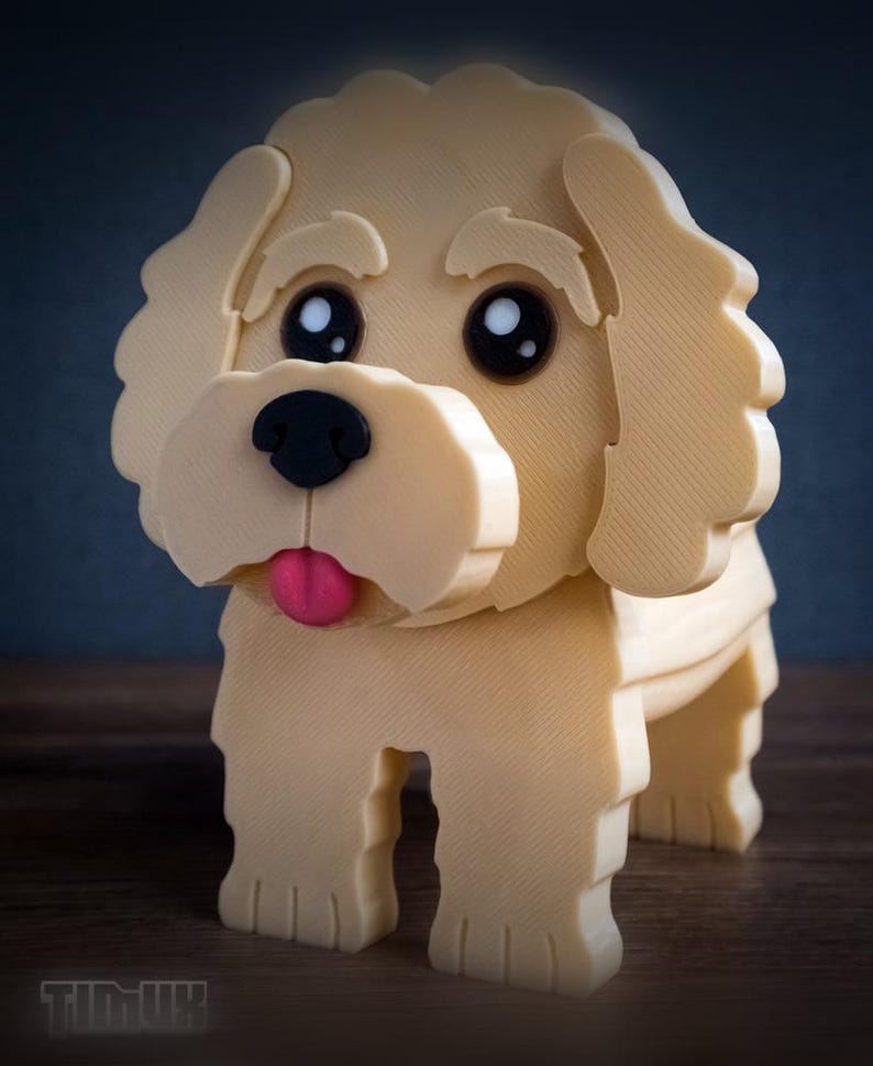 May include: A 3D printed cream-colored dog figurine with large black eyes, a black nose, and a small pink tongue. The figure features textured, layered surfaces and the word TIMUX is embossed in the lower left corner of the image.