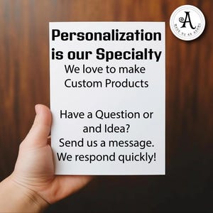 May include: A white card held by a hand with the text "Personalisation is our Speciality" and "We love to make Custom Products". The card also says "Have a Question or and Idea? Send us a message. We respond quickly!"