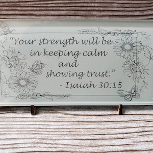 May include: A glass plaque with a floral design and the quote "Your strength will be in keeping calm and showing trust." - Isaiah 30:15