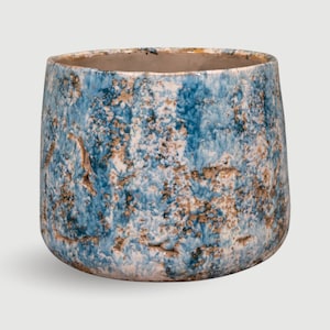 May include: A ceramic plant pot with a textured finish. The pot is a mix of blue, white, and brown hues. The round pot has a wide opening and a thick base. The inside of the pot is a neutral beige colour.