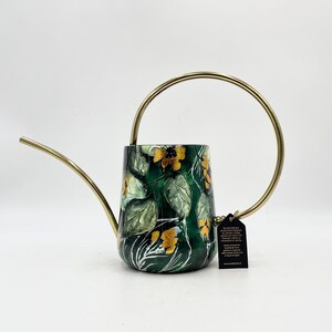 May include: A green watering can with a gold handle and a floral design. The can has a spout and a tag attached to the handle.