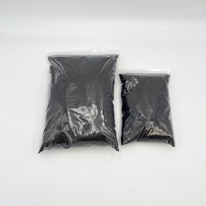 May include: Two plastic bags filled with black soil. The larger bag is about twice the size of the smaller bag.