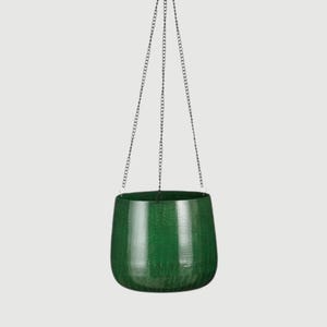 May include: A dark green hanging planter with a textured finish. The round pot is suspended by three chains attached to a metal ring. Suitable for indoor or outdoor use, it's a stylish plant pot.