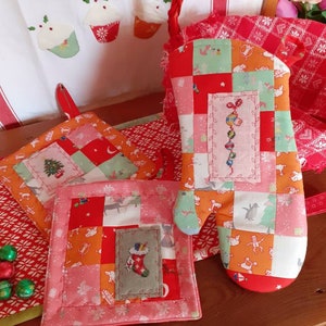 Peut inclure: Trois maniques de cuisine en patchwork rouge et blanc avec des motifs de Noël brodés. Les maniques sont faites de différents tissus et présentent une variété de motifs de Noël, notamment un sapin de Noël, une chaussette et une canne en sucre.