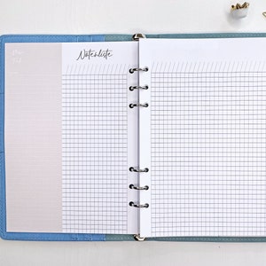 Könnte beinhalten: Ein blauer Ordner mit einer weißen Seite, die auf einen karierten Abschnitt mit der Aufschrift "Notizenliste" geöffnet ist. Die linke Seite hat einen einfachen weißen Hintergrund.