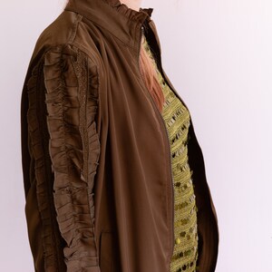 May include: A brown bomber jacket with a zipper closure and ruffled detailing on the sleeves.