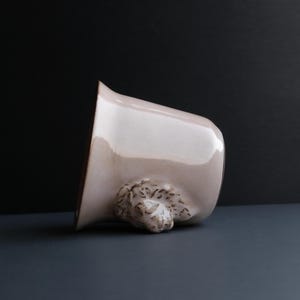 May include: A light pink ceramic mug with a brown textured handle shaped like a bear's head.