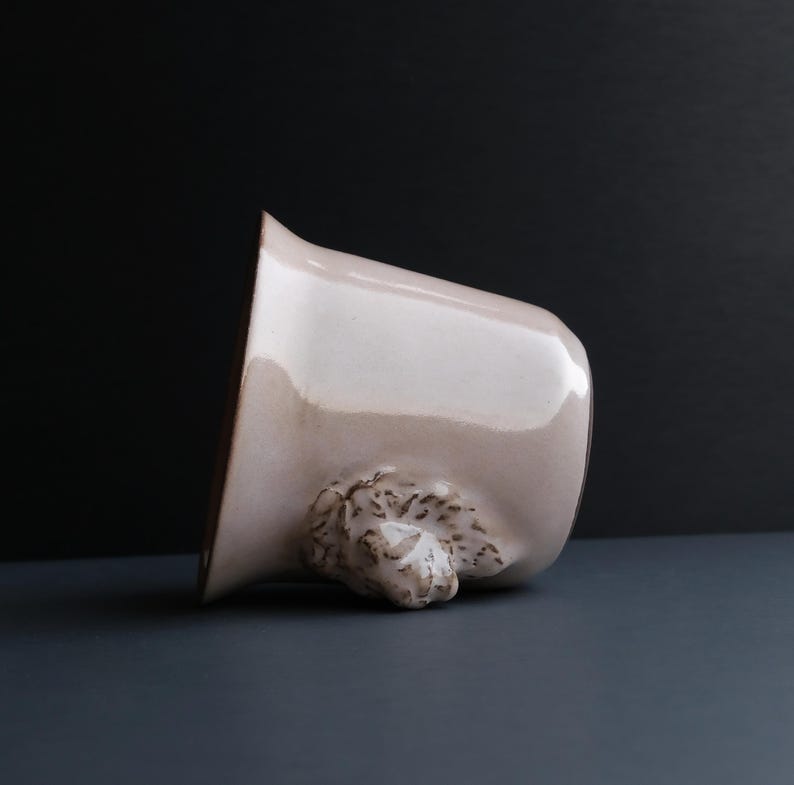 May include: A light pink ceramic mug with a brown textured handle shaped like a bear's head.