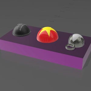 May include: Three dome-shaped objects in black, red, and silver, and a silver ring, are displayed on a purple rectangular block. The red dome has a yellow star design. The objects are likely decorative or functional items.