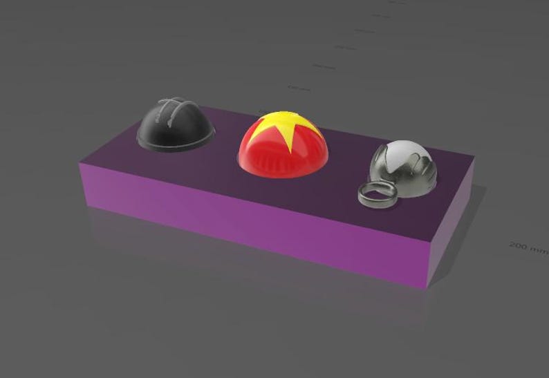 May include: Three dome-shaped objects in black, red, and silver, and a silver ring, are displayed on a purple rectangular block. The red dome has a yellow star design. The objects are likely decorative or functional items.