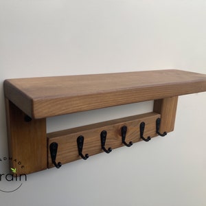 May include: A wooden shelf with six black metal hooks, labeled "Handmade Grain".