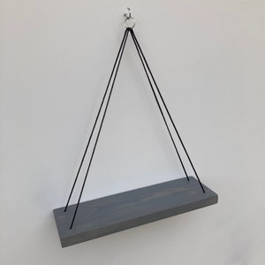 以下が含まれることがあります： 黒い紐で天井から吊り下げられた灰色の木製棚。棚の長さは約30cmです。
