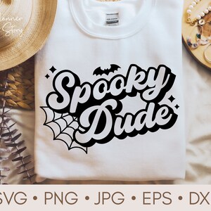 May include: White t-shirt with a black graphic that says "Spooky Dude" in a retro font. The graphic also includes a spider web and a bat.