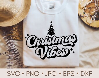 May include: White t-shirt with a black Christmas tree and the text "Christmas Vibes" in a retro font.