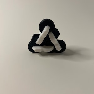 May include: A black and white triangular puzzle with interlocking pieces. The puzzle is made of plastic and has a smooth finish.