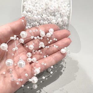 May include: A strand of white pearl garland with small and large pearls strung on clear thread.