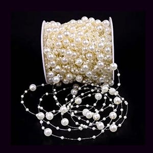 May include: A spool of white pearl garland with a string of pearls hanging off the spool. The garland is made of small white pearls strung on a thin wire.