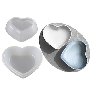 May include: Three heart-shaped bowls, two are white and one is light blue. The bowls are made of ceramic and have a smooth, glossy finish.