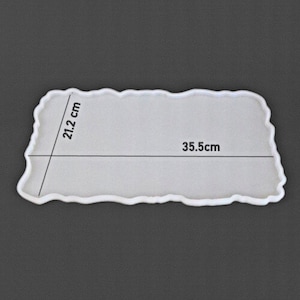 May include: A white rectangular resin mould with a wavy edge. The mould measures 21.2 cm by 35.5 cm. The mould is designed for creating decorative trays or similar items.