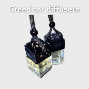 K&ouml;nnte beinhalten: Zwei schwarze Autodiffusoren mit einer schwarzen Schnur, die daran h&auml;ngt. Die Diffusoren sind mit einer klaren Fl&uuml;ssigkeit gef&uuml;llt und haben ein dekoratives Design.