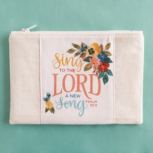May include: A white canvas zippered pouch with a floral design and the text "Sing to the Lord a new song Psalm 33:3".