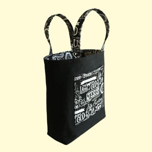 This black canvas bible bag has two outside pockets and two inside pockets made from blackk cotton fabric with names of God in white pattern. The Christian tote bag is lined.
