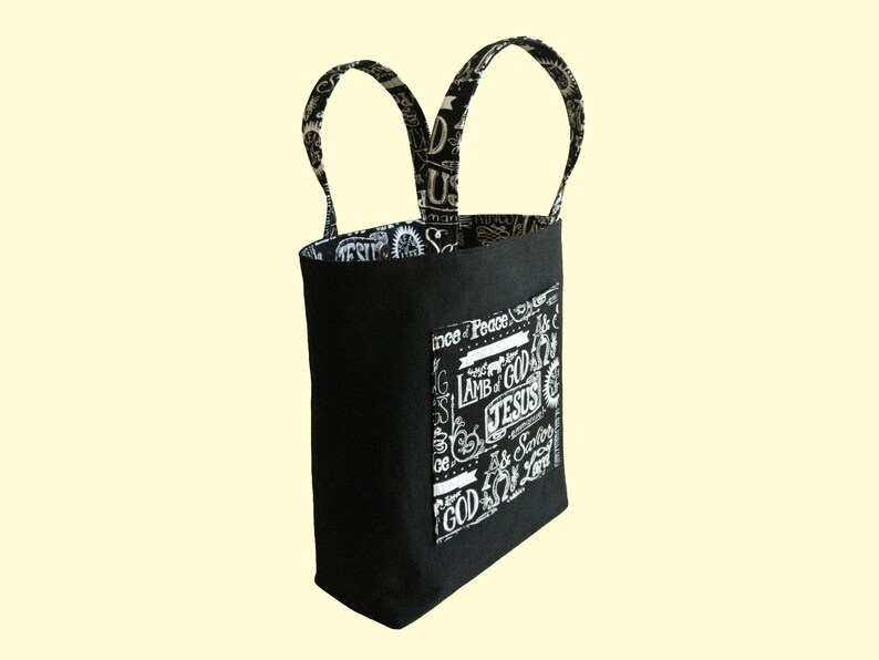 This black canvas bible bag has two outside pockets and two inside pockets made from blackk cotton fabric with names of God in white pattern. The Christian tote bag is lined.