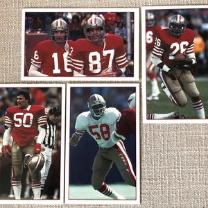 May include: Five vintage football trading cards featuring players in red and white uniforms. The players are wearing helmets and holding footballs. The cards have the players' numbers on them, including 16, 87, 26, 50, and 58.