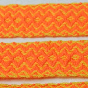 May include: Three woven strips of fabric in a diamond pattern. The fabric is orange and yellow.