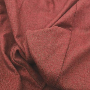 May include: Close-up of a red herringbone fabric with a textured surface.