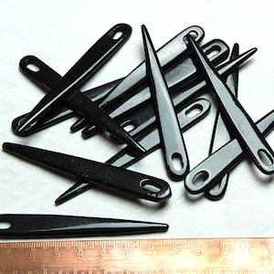 Puede incluir: Un montón de enhebradores de aguja de plástico negro. Los enhebradores miden aproximadamente 10 cm de largo y tienen un pequeño bucle en un extremo.