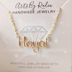May include: Gold necklace featuring the name "Hayah" crafted from wire. The necklace is displayed against a white backdrop with the text "Arts By Ralia Handmade Jewelry" above and "Beautiful Jewelry Made With Care And Attention" below.
