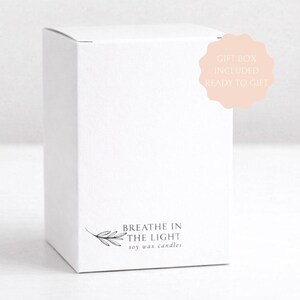 以下が含まれることがあります： 小さな黒い植物のイラストと下部に「BREATHE IN THE LIGHT SOY WAX CANDLES」という文字が印刷された、無地の白い長方形の段ボール箱。薄いピンク色のスカラップ状の円形バッジには「GIFT BOX INCLUDED READY TO GIFT」という文字が表示されています。